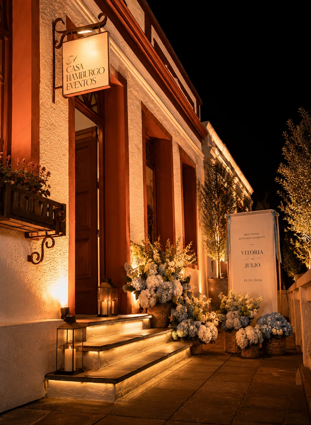 Varanda da fachada iluminada à noite com velas e arranjos florais